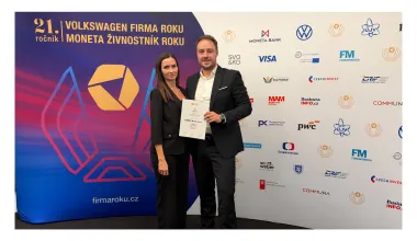 Two people holding the LOMAX certificate in front of the Firma roku 2026 event backdrop