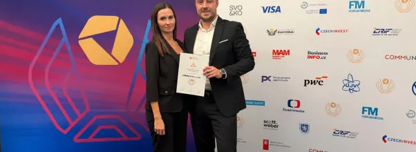 Two people holding the LOMAX certificate in front of the Firma roku 2026 event backdrop