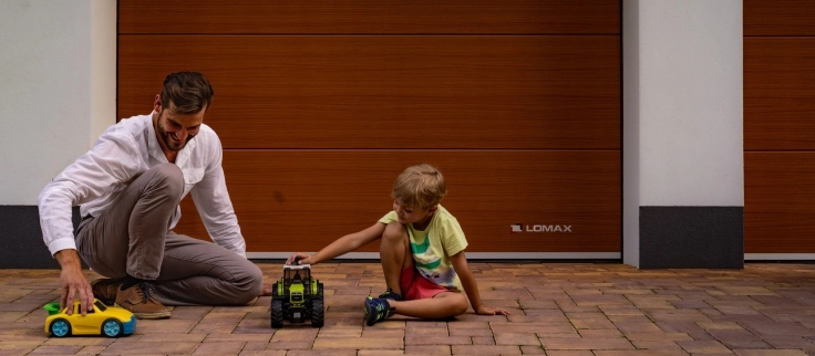 Father and son with toys in front of a LOMAX garage door